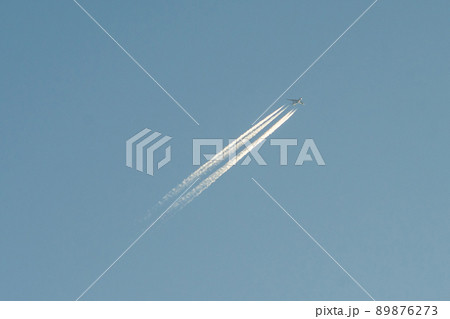 A plane with a reversible trail following it in the blue sky. A plane with a reversible trail following it in the blue sky. 89876273