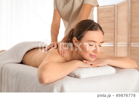 Young woman having body scrubbing procedure with sea salt in spa salon 89876778