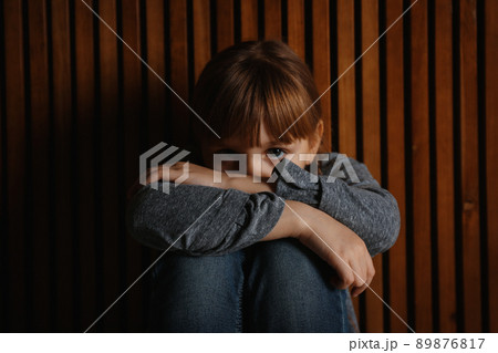 Sad little girl on wooden background. Child in danger 89876817