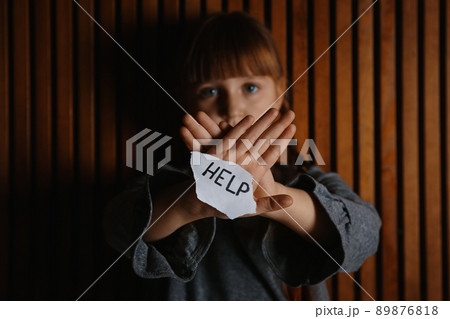 Sad little girl with sign HELP on wooden background. Child in danger 89876818