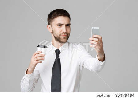 Lifestyle and Business Concept - Portrait of a handsome businessman enjoy taking a selfie with take away cup of coffee. Isolated White background. Copy Space. Lifestyle and Business Concept - Portrait of a handsome businessman enjoy taking a selfie with take away cup of coffee. Isolated White background. Copy Space. 89879494