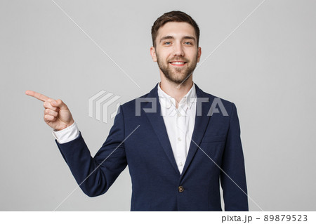 Young successful businessman pointing direction with finger over dark grey background. Copy space. 89879523