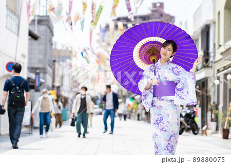 鯉のぼりのある川越大正浪漫夢通りで浴衣で和傘でポージングする女性 89880075