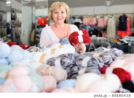 Mature woman buyer choosing colored yarn for knitting on sale Mature woman buyer choosing colored yarn for knitting on sale 89880438