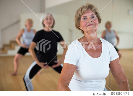 Mature women perform a plie squat while in the position of a ballet stand Mature women perform a plie squat while in the position of a ballet stand 89880472