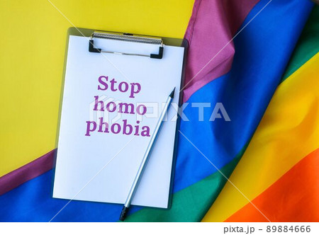 Rainbow flag with text STOP HOMOPHOBIA message paper note. Rainbow lgbtq flag made from silk material. Symbol of LGBTQ pride month. Equal rights Rainbow flag with text STOP HOMOPHOBIA message paper note. Rainbow lgbtq flag made from silk material. Symbol of LGBTQ pride month. Equal rights 89884666