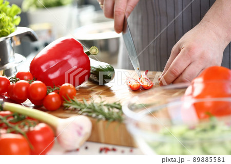 Male chef cutting hot pepper with sharp knife, veggies on cutting board, enjoy cooking Male chef cutting hot pepper with sharp knife, veggies on cutting board, enjoy cooking 89885581