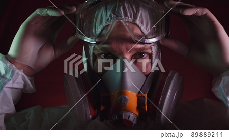 Man in protective costume suit, gas protect medical spray paint mask. Doctor in respirator. Concept health virus coronavirus epidemic. Man in protective costume suit, gas protect medical spray paint mask. Doctor in respirator. Concept health virus coronavirus epidemic. 89889244