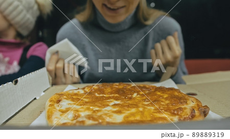 Girl eat pizza cheese four. Close up of young woman mouth greedily eating pizza and chewing in outdoor restaurant. Junk food. Pizza from open box. 89889319