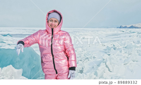 Girl walking on cracked ice of a frozen lake Baikal. Woman trave 89889332