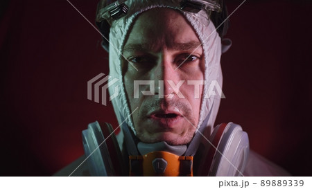 Man in protective costume suit, gas protect medical spray paint mask. Doctor in respirator. Concept health virus coronavirus epidemic. Man in protective costume suit, gas protect medical spray paint mask. Doctor in respirator. Concept health virus coronavirus epidemic. 89889339