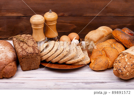 Assortment of baked bread and rolls on white and brown background. 89891572