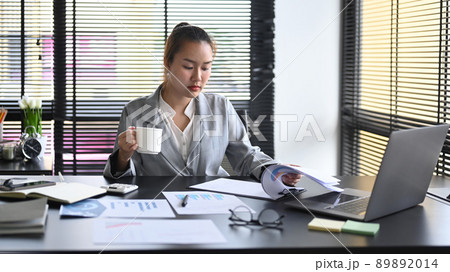 Professional businesswoman drinking coffee and working at modern office Professional businesswoman drinking coffee and working at modern office 89892014