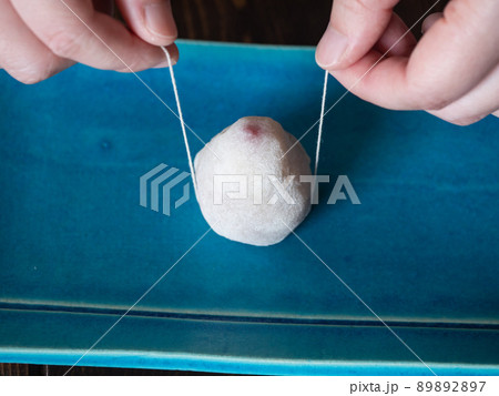 フルーツ大福を糸で半分にカットするところ。真っ赤な苺を求肥と白餡で包んだ和菓子。 89892897