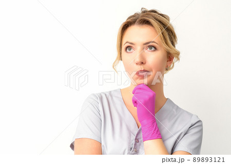Young caucasian female doctor wearing gloves thoughtful looking away isolated on white background Young caucasian female doctor wearing gloves thoughtful looking away isolated on white background 89893121