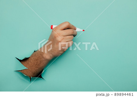 A man writes a marker on a broken blue paper wall A man writes a marker on a broken blue paper wall 89894461