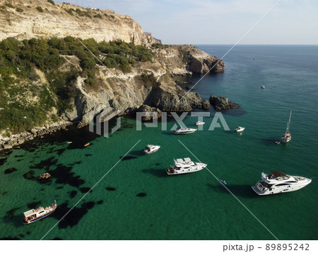 Aerial panoramic view of seascape with crystal clear azure sea and rocky shores. Yachts in a beautiful lagoon on backdrop of rocks. The concept of an ideal destination for summer travel and vacation. Aerial panoramic view of seascape with crystal clear azure sea and rocky shores. Yachts in a beautiful lagoon on backdrop of rocks. The concept of an ideal destination for summer travel and vacation. 89895242
