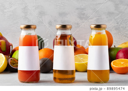 Various fruits and freshly squeezed fruits juice in bottle on gray background Various fruits and freshly squeezed fruits juice in bottle on gray background 89895474
