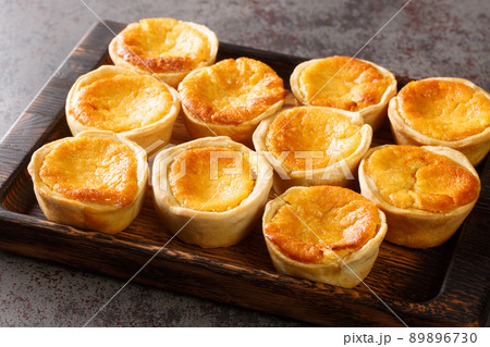 Portuguese cheese Tarts Queijadas are a sweet, creamy, traditional dessert close-up on a wooden tray. Horizontal 89896730