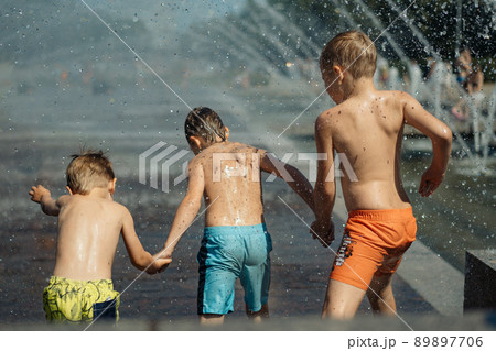 Three caucasian boys going to run throgh splashing fountain on hot summer day in city of Saint-petersburg, Russia Three caucasian boys going to run throgh splashing fountain on hot summer day in city of Saint-petersburg, Russia 89897706