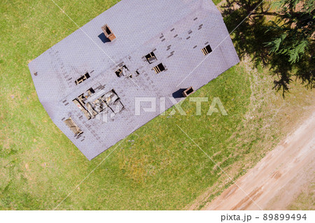 Damaged roof of an roofing shingles on a old rural house residential rooftop Damaged roof of an roofing shingles on a old rural house residential rooftop 89899494