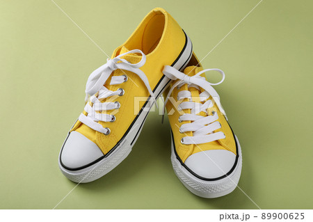 Pair of yellow sneakers on green background Pair of yellow sneakers on green background 89900625