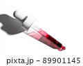 Liquid red oil serum drop in pipette isolated on white background. Retinol, aha acid, collagen skincare fluid, close up photo with shallow depth of field. Transparent crimson essence in dropper 89901145