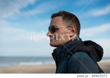 Ostend, West Flanders Belgium, Attractive fourty year old man with blue jacket and sunglasses posing at the belgian seaside Ostend, West Flanders Belgium, Attractive fourty year old man with blue jacket and sunglasses posing at the belgian seaside 89902073