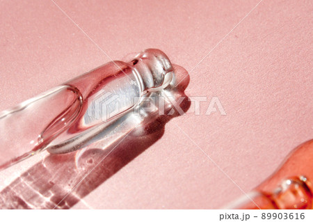Pipette with fluid hyaluronic acid on pink background. Cosmetics and healthcare concept closeup. Dose of serum, retinol with air bubbles. Flat lay. Luxury beauty product presentation, macro 89903616