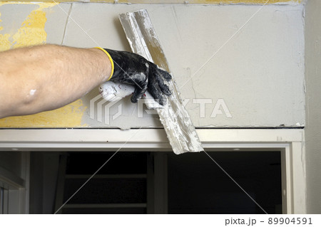 The plasterer plasters the wall with a putty knife The plasterer plasters the wall with a putty knife 89904591