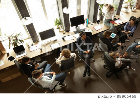 Working process at modern business company. Young men and women discussing something with coworkers, sitting at office table. Concept of team, job, career 89905469