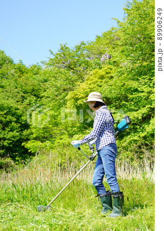 草刈り機を操作する中年女性の後ろ姿 89906249