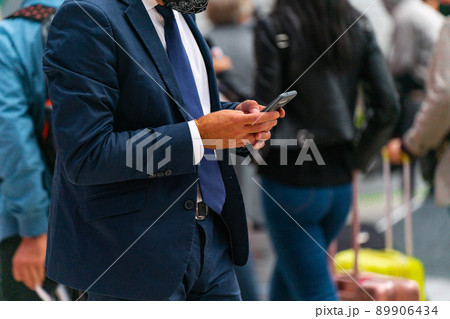 An unidentified man in a blue suit walks and types on his phone while walking with two hands An unidentified man in a blue suit walks and types on his phone while walking with two hands 89906434