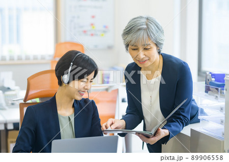オフィスで打ち合わせするシニア世代の上司とミドル世代の女性オペレーター オフィスで打ち合わせするシニア世代の上司とミドル世代の女性オペレーター 89906558