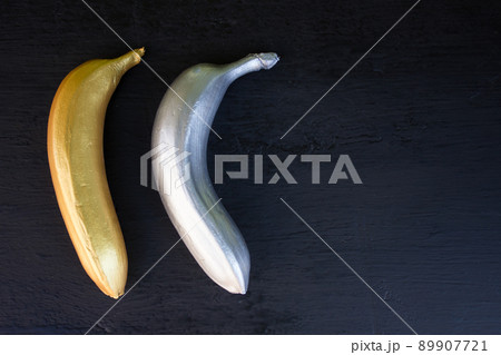 Golden and silver banana on a black background. Trend concept, horizontal frame Golden and silver banana on a black background. Trend concept, horizontal frame 89907721