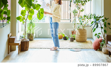 部屋の観葉植物に水をあげる女性 89907867