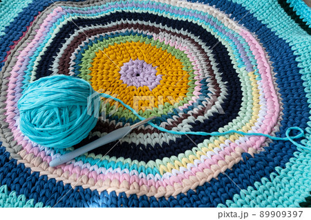A rug made of knitted yarn and a crochet hook. Home needlework. 89909397