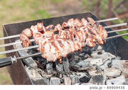 Marinated shashlik preparing on a barbecue grill over charcoal. Shashlik or Shish kebab popular in Eastern Europe 89909436