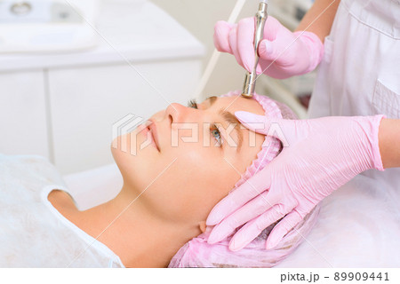 Image of a young beautiful woman dressed as a patient, lying on a couch in a cosmetology clinic. 89909441