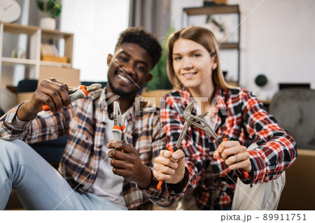 Multiracial couple holding repair instruments at home 89911751
