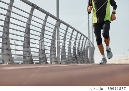 Horizontal shot of unrecognizable senior man wearing modern sportswear jogging in the morning 89911877