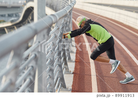 Horizontal side view of modern senior man wearing tracksuit doing aerobic exercise 89911913