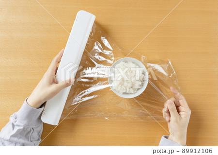 食品用のラップを用いてご飯を保存する女性。 89912106