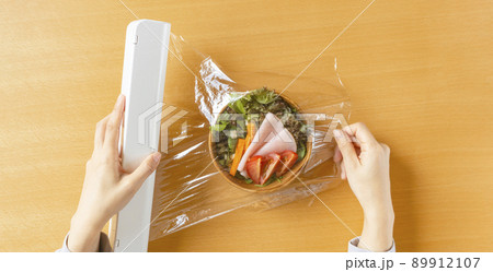 食品用保存のラップを用いてサラダを保存する女性。食品保存、鮮度を保つなど 89912107
