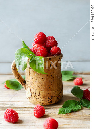 Raspberries in the corkwood cup on the wooden table with leaves Raspberries in the corkwood cup on the wooden table with leaves 89912190
