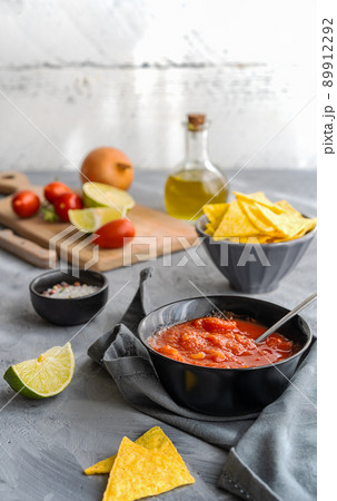 Tomato dip with nachos tortilla in bowl and main ingredients aside Tomato dip with nachos tortilla in bowl and main ingredients aside 89912292