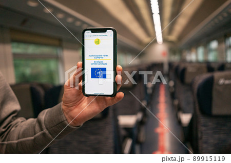A man's hand holds a phone with a green pass italy on the train during a vaccination check A man's hand holds a phone with a green pass italy on the train during a vaccination check 89915119