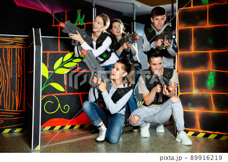 Modern young people with laser pistols playing laser tag on dark labyrinth 89916219
