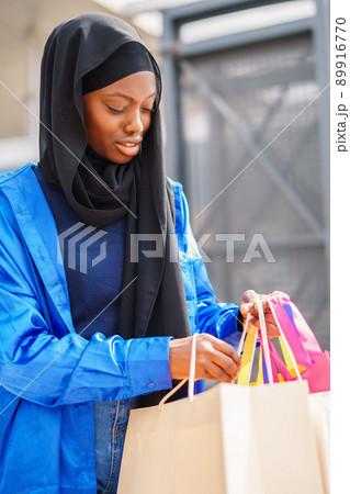 Muslim shopaholic checking purchases in paper bags Muslim shopaholic checking purchases in paper bags 89916770