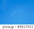 月と飛行機雲、青い背景素材 89917033